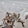 Home gym with exercise bikes, treadmills, free weights, and benches in a bright, modern room with light flooring.