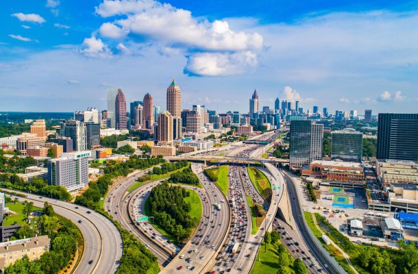 Aerial view of downtown Atlanta with highways, tall buildings, and a partly cloudy sky.