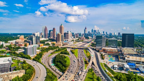 Aerial view of downtown Atlanta with highways, tall buildings, and a partly cloudy sky.